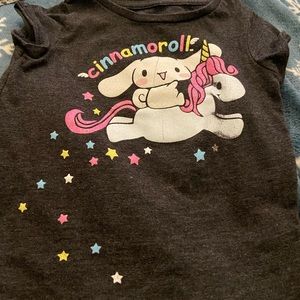 This is a dark-colored T-shirt featuring Cinnamoroll, laying on top of a cloud